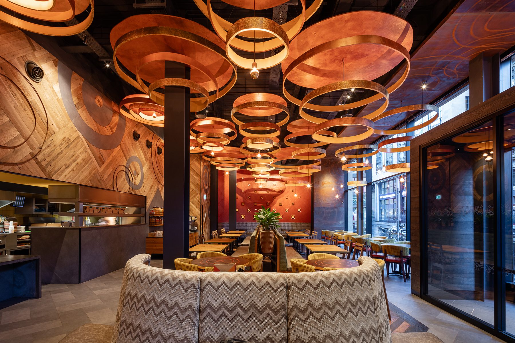Nando's Waterloo Street, Glasgow. Wide dining room beneath suspended copper-ring ceiling installations.
